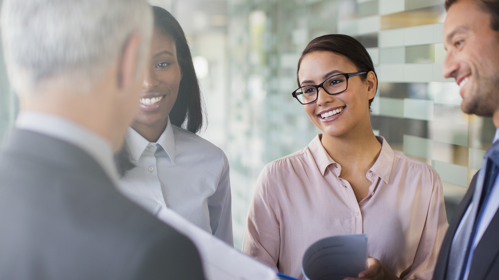 Business men and women exchanging greetings in office.