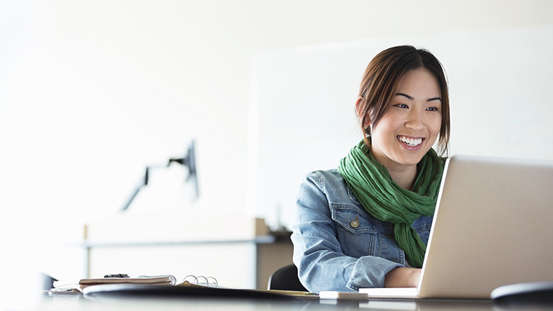 Woman in scarf smiling at laptop